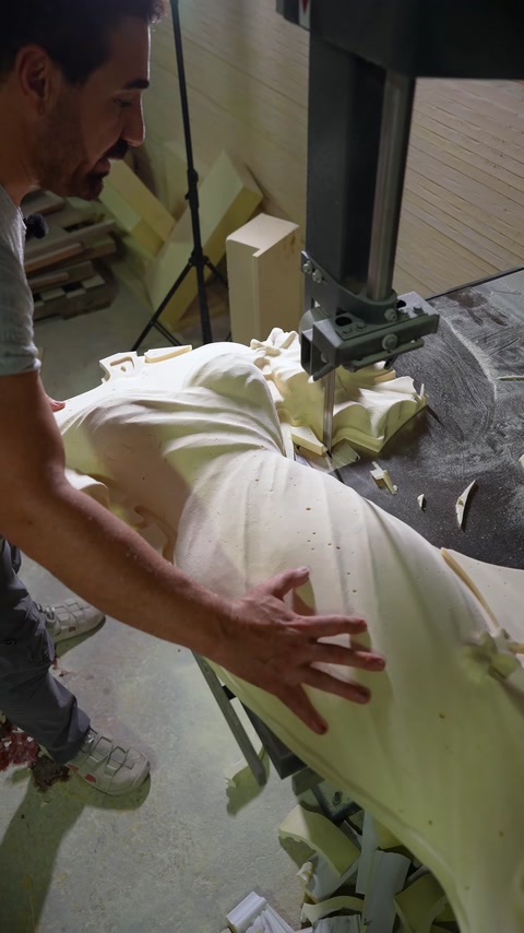 Un artigiano leviga a mano una scultura in rilievo in poliuretano intagliata