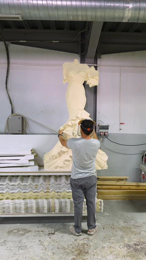 Un operaio solleva una grande figura scolpita in rilievo nuziale nel laboratorio