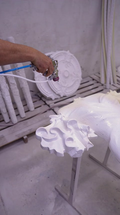 Un tecnico spruzza il rivestimento su un rosone da soffitto in poliuretano