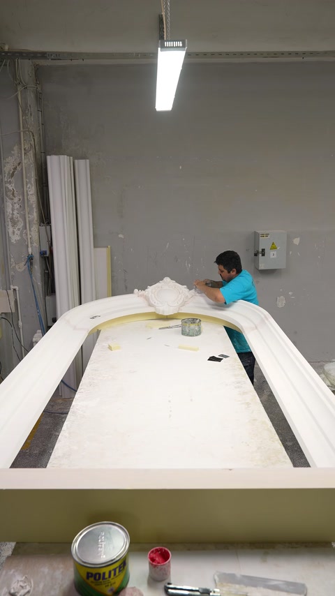 Un operaio assembla una grande struttura in poliuretano a forma d'arco nel laboratorio