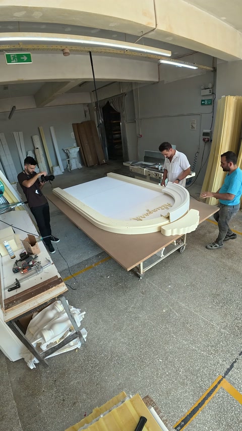 Workers position layered polyurethane sections around the large arched panel.