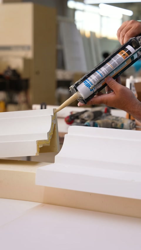 Adhesive is dispensed along the joint of white molding sections.