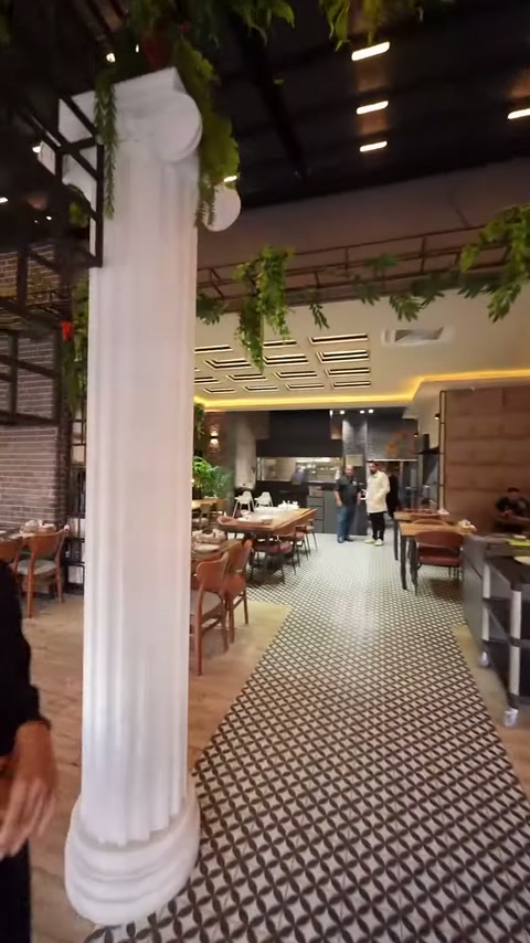Tamamlanmış yivli dekoratif sütun, restoran masalarının yanında konumlanıyor.