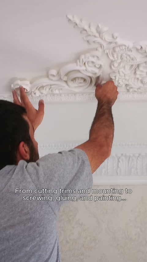 Un elemento di cornice decorativa elaborato viene posizionato a mano all'angolo parete-soffitto.
