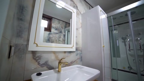 A bathroom with a shower enclosure, vanity unit, and window details