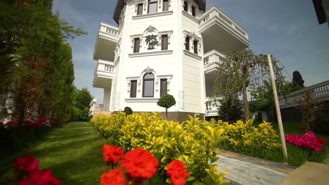 A villa with trimmed windows and facade bands surrounded by landscaping