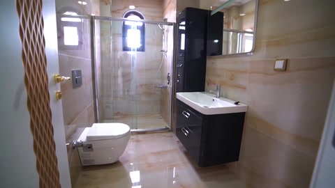 A bathroom with a vanity cabinet, toilet, and marble-look surfaces
