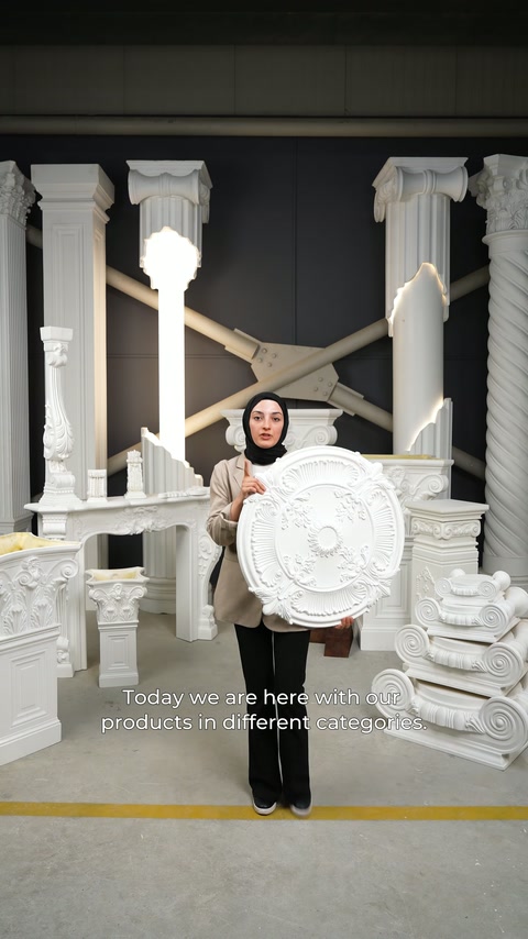 A presenter in the showroom displays a round ceiling rose in front of column models.