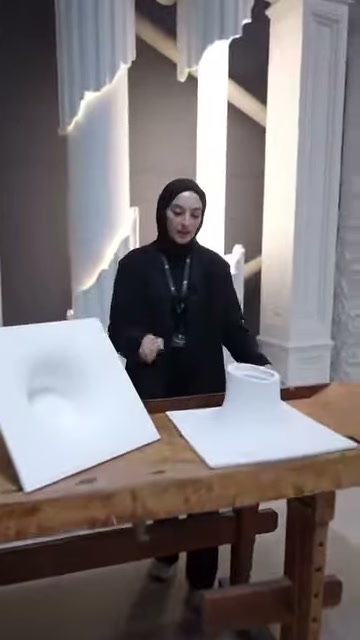 Il conduttore presenta due modelli di plafoniere poliuretaniche amorfe sul tavolo della sala espositiva