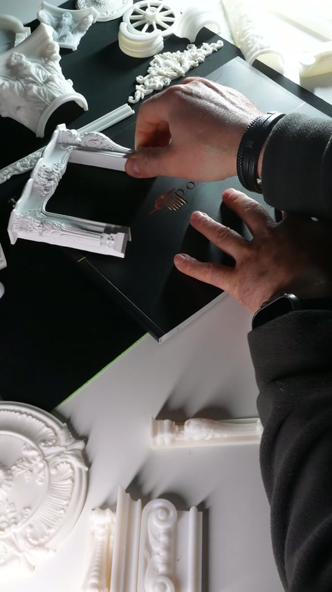 La mano avvicina il pezzo di ornamentazione orizzontale all'angolo della cornice
