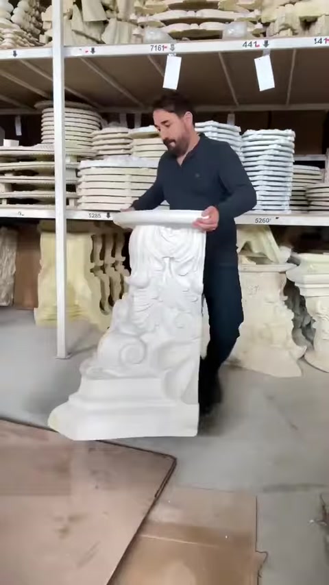 Un artigiano esamina un modello di capitello con grandi motivi a foglia