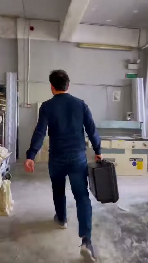 L'addetto trasporta la borsa dell'attrezzatura verso l'area di lavoro dell'officina.