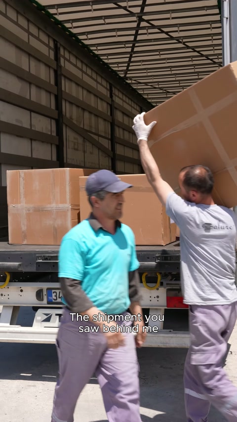 Two workers lift a large cardboard box into the truck bed.