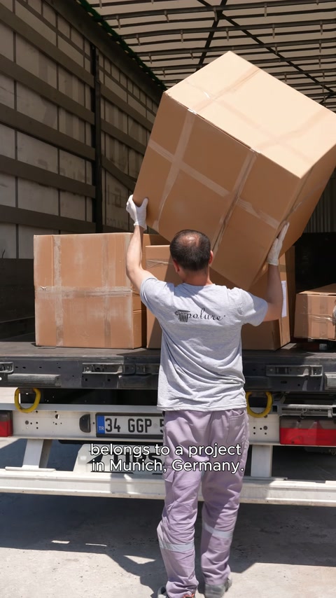 Workers place a bulky product package together into the open truck.