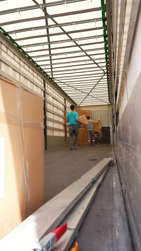A worker checks the arrangement of packaged products inside the vehicle.