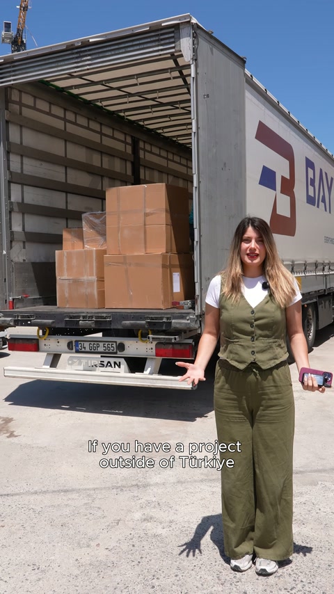 The presenter speaks in front of an open delivery truck filled with boxes.