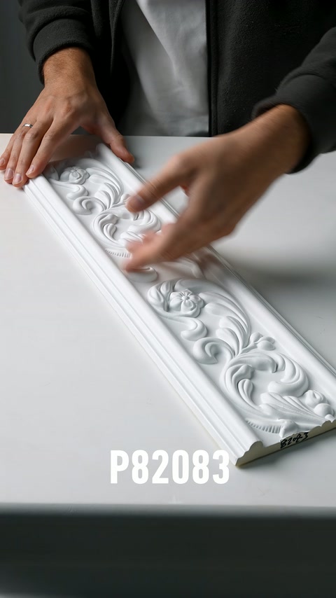 Le dita scorrono sulla superficie di una fascia decorativa bianca con motivi floreali