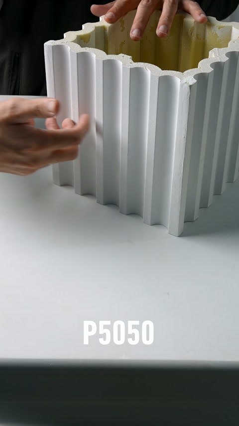 Il corpo decorativo bianco scanalato viene tenuto in posizione verticale con entrambe le mani