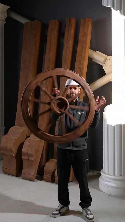 Presentatore tiene un modello di ruota effetto legno decorativo davanti a sé nell'area espositiva del laboratorio.