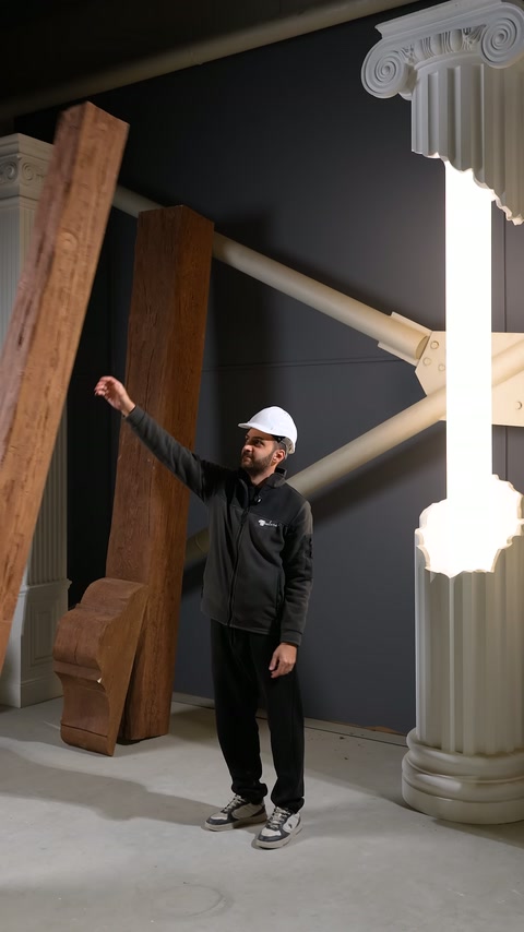 Presentatore indica modelli di trave in tonalità di legno diversi appoggiati al muro.