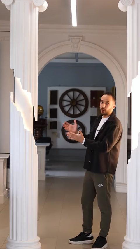 Presenter gesturing beside illuminated columns in decorated showroom