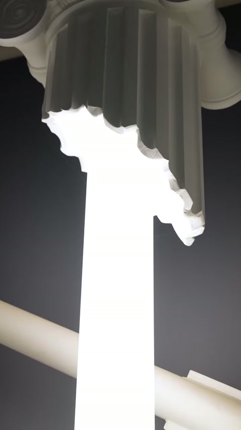 Angled close-up shows capital detailing above the luminous column core.