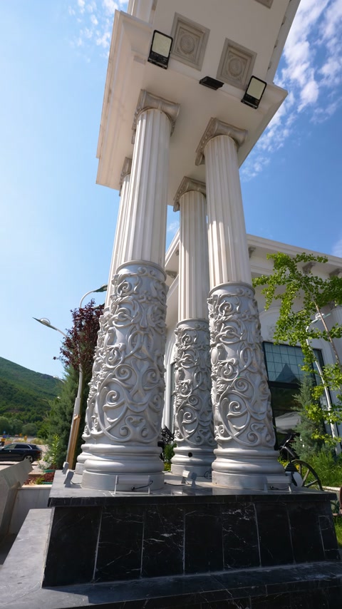 Decorative entrance arch with fluted columns and botanical motifs beneath.