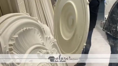A worker stands beside vertically stacked decorative ceiling medallions