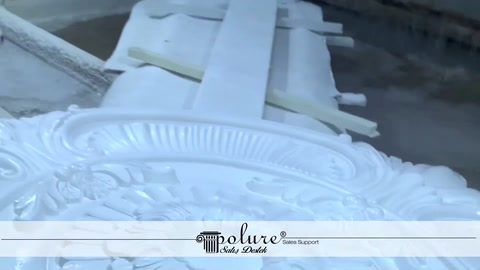 White ceiling medallion pieces are placed on a workbench in the production area