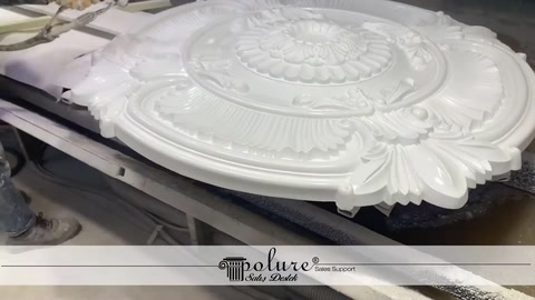 A large round ceiling medallion lies horizontally on the workbench