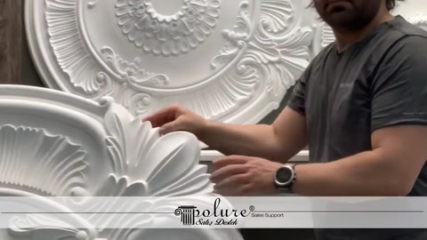 A craftsman holds an embossed ceiling medallion to show its details