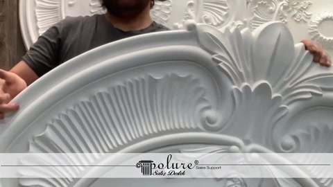 A craftsman displays a ceiling medallion with a wide border in an upright position