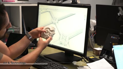 Two small decorative connector elements compared by hand in front of computer