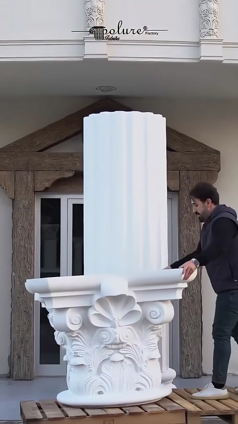 A Corinthian capital is prepared in front of a fluted column shaft