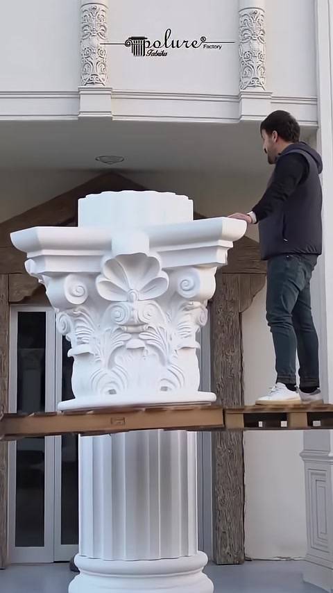 A Corinthian column capital with botanical relief details is displayed up close