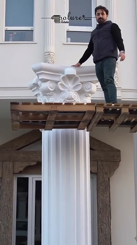 A Corinthian capital is placed onto the fluted shaft from scaffolding