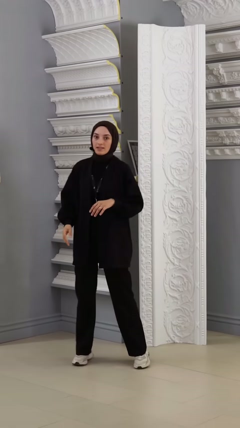 Sunucu, dekoratif profiller ve kabartmalı paneller arasında tanıtım yapıyor.