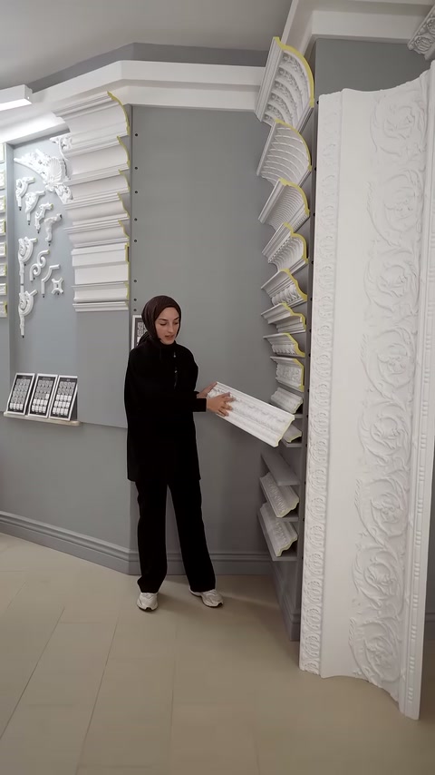 Sunucu, elindeki beyaz kartonpiyer kesitini izleyiciye doğru tutuyor.
