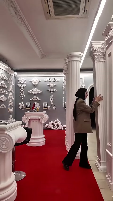 Capitello di colonna con decorazioni botaniche esposto su tappeto rosso