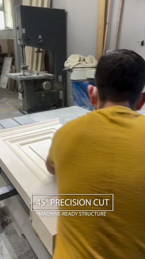Worker machine-cuts a decorative polyurethane panel at a precise angle.