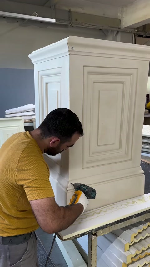 Worker prepares the lower edge of a paneled pedestal.