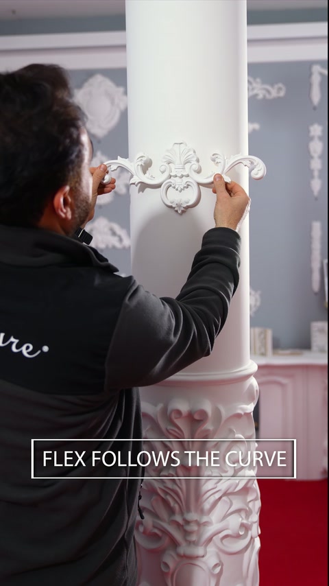 Installer positions a flexible decorative motif around a curved column.