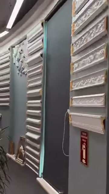 Cornices are presented in two vertical groups on a gray display wall