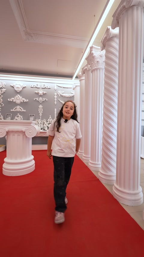 Nel corridoio della showroom con tappeto rosso sono allineate colonne decora tive scanalate.