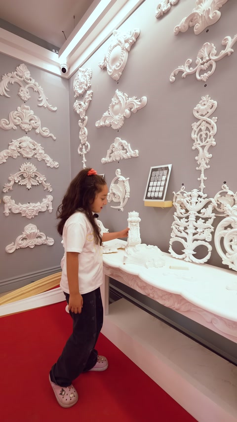 La presentatrice mostra decorazioni lavorate davanti ad applique in rilievo.