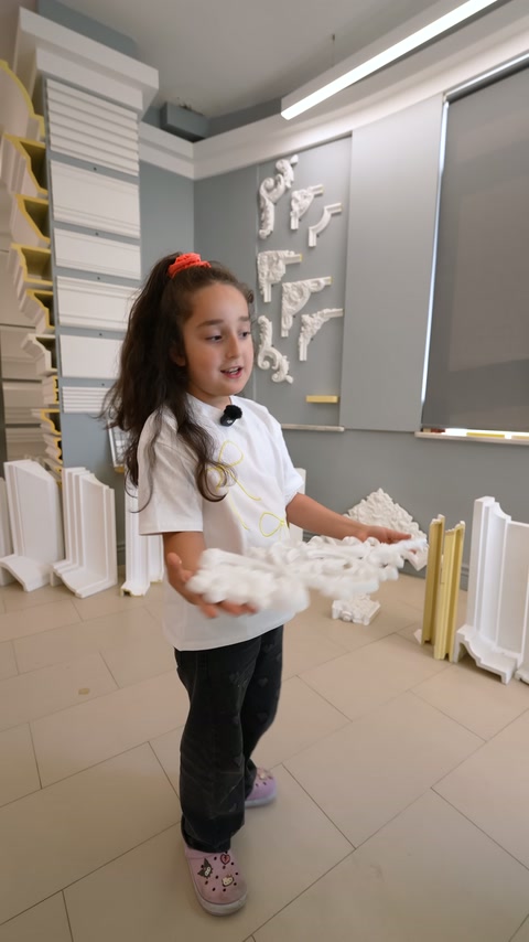 La giovane presentatrice trasporta un grande elemento di decorazione bianca.