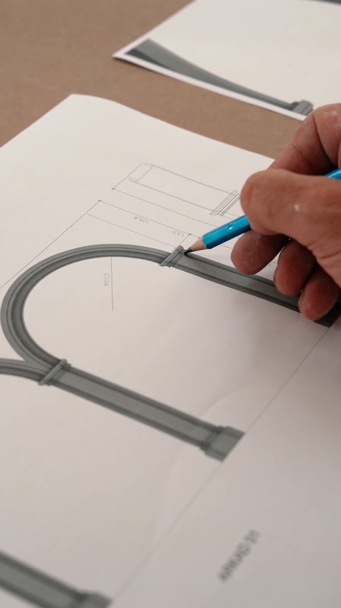 Mano che disegna la geometria del profilo dell'arco su carta tecnica