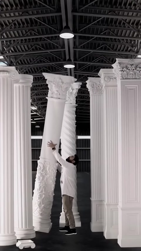 A worker positions a tall, ornately detailed column section