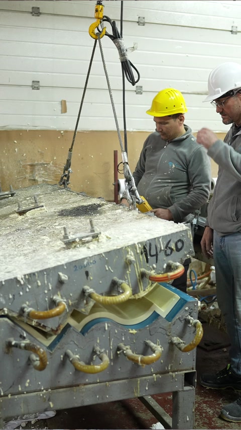 Workshop technician operates lifting equipment beside an ornate mould.