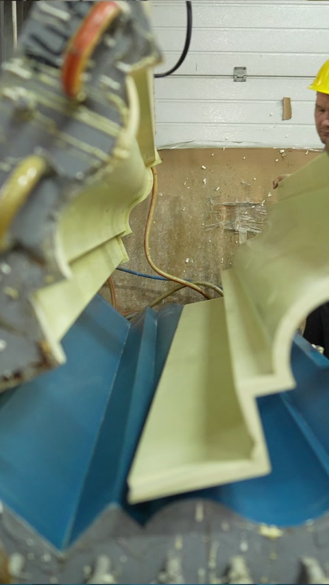 Machining equipment shapes an ornamental polyurethane profile in the workshop.